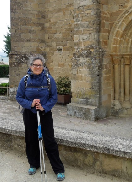 woman standing with hiking gear in front of an old buildling